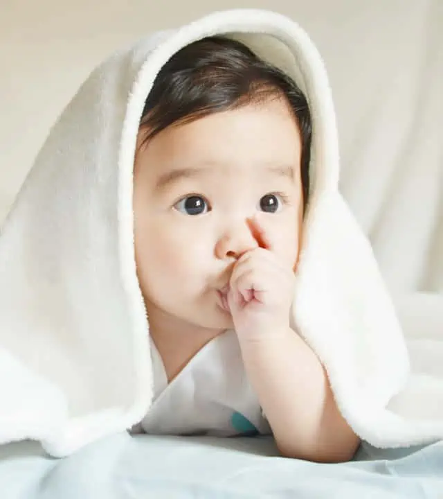 young asian baby sucking on his thumb