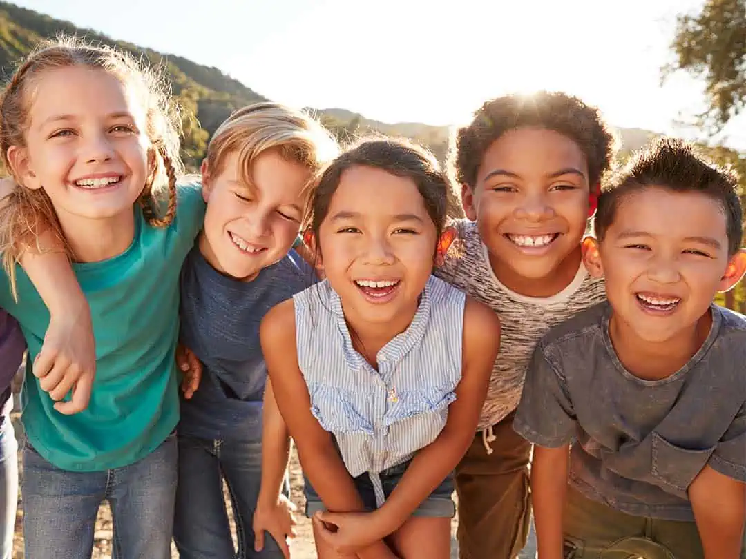 Kids smiling at the camera, holding each other