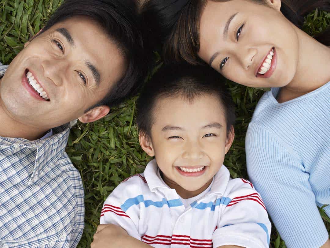 Young Asian family laid back on the grass.